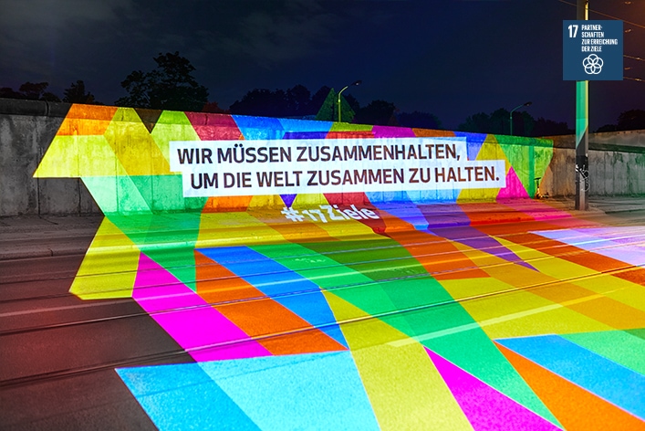 Projektion zu Ziel 17 an der Berliner Mauer: Wir müssen zusammenhalten, um die Welt zusammen zu halten. © Engagement Global/Kolja Schmidt