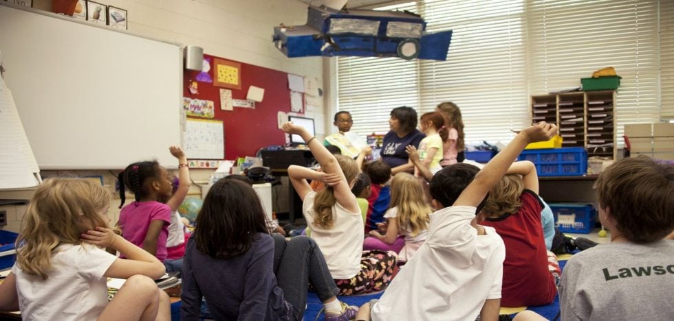 Kinder sitzen zusammen in Klassenraum.